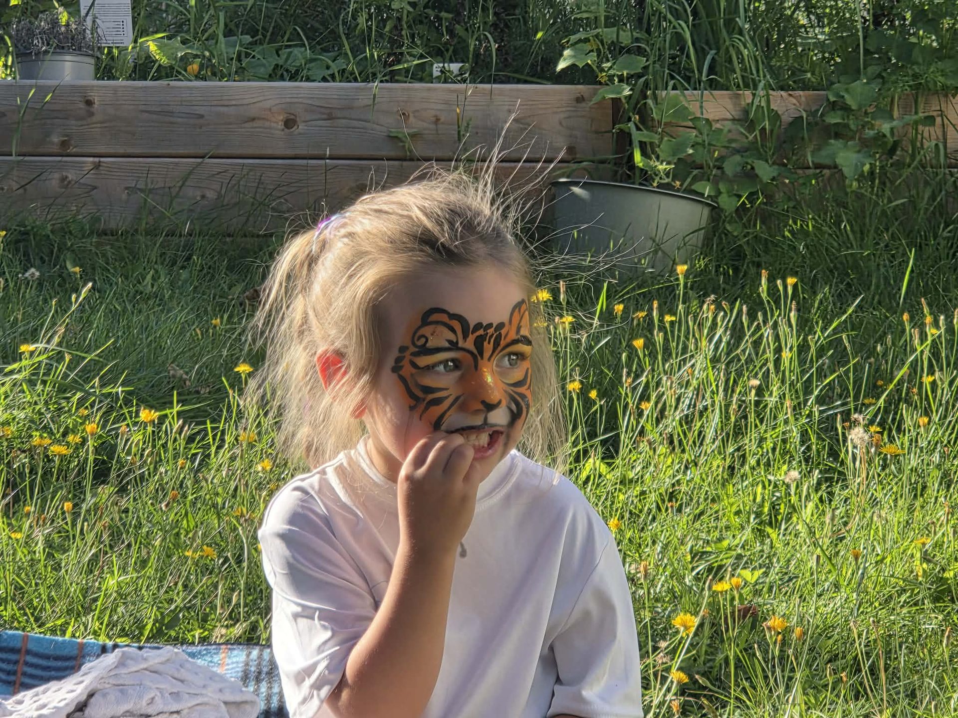 Fillette maquillée en tigre qui rigole dans un jardin fleuri