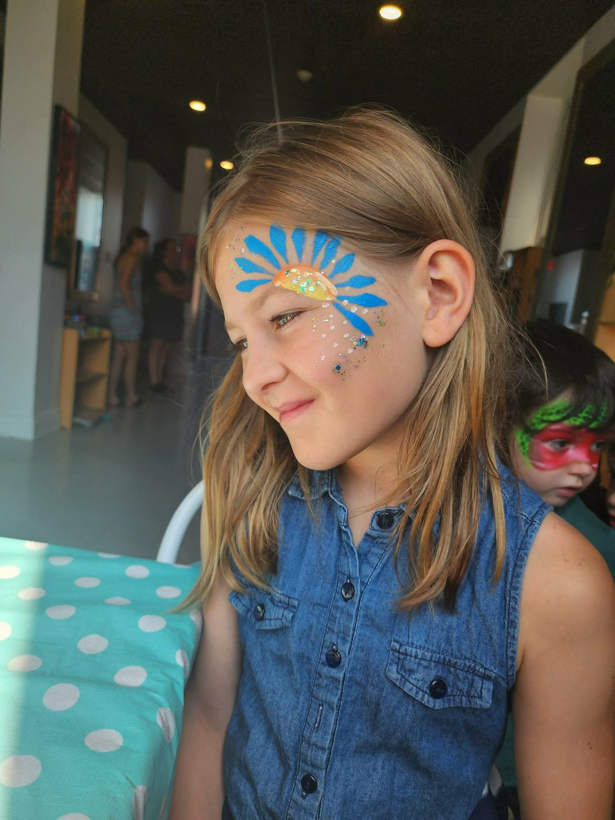 Maquillage de pétales bleus et paillettes autour de l'œil d'une fillette